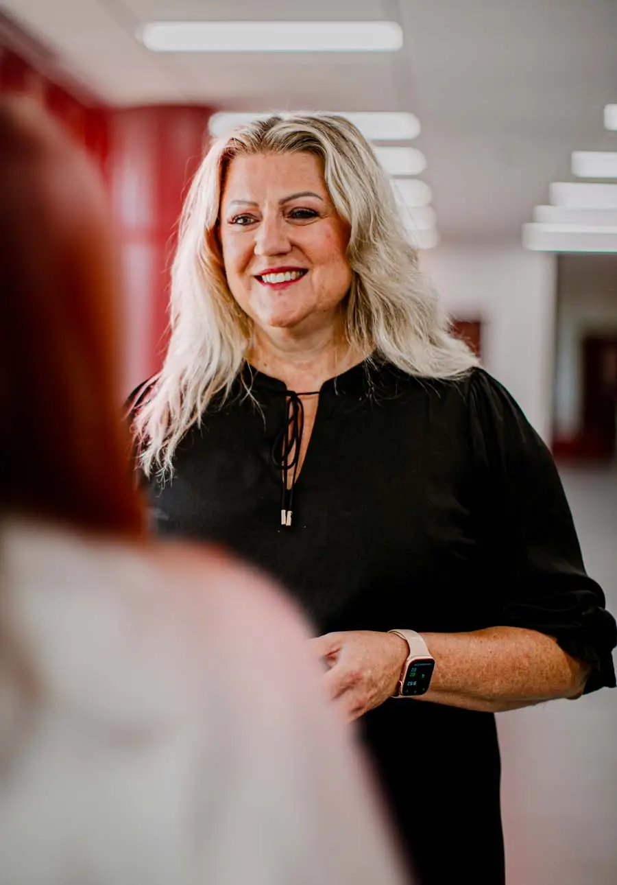Faculty member speaking with a student in a campus hallway with modern interior design and natural light