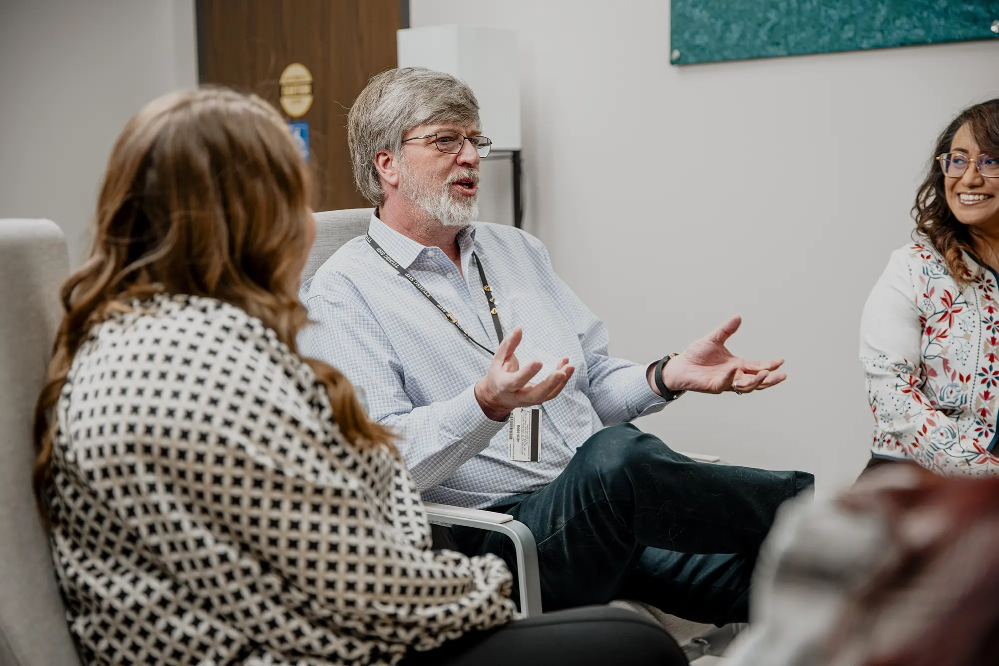 People seated in a counseling group discussion inside a clinic meeting room