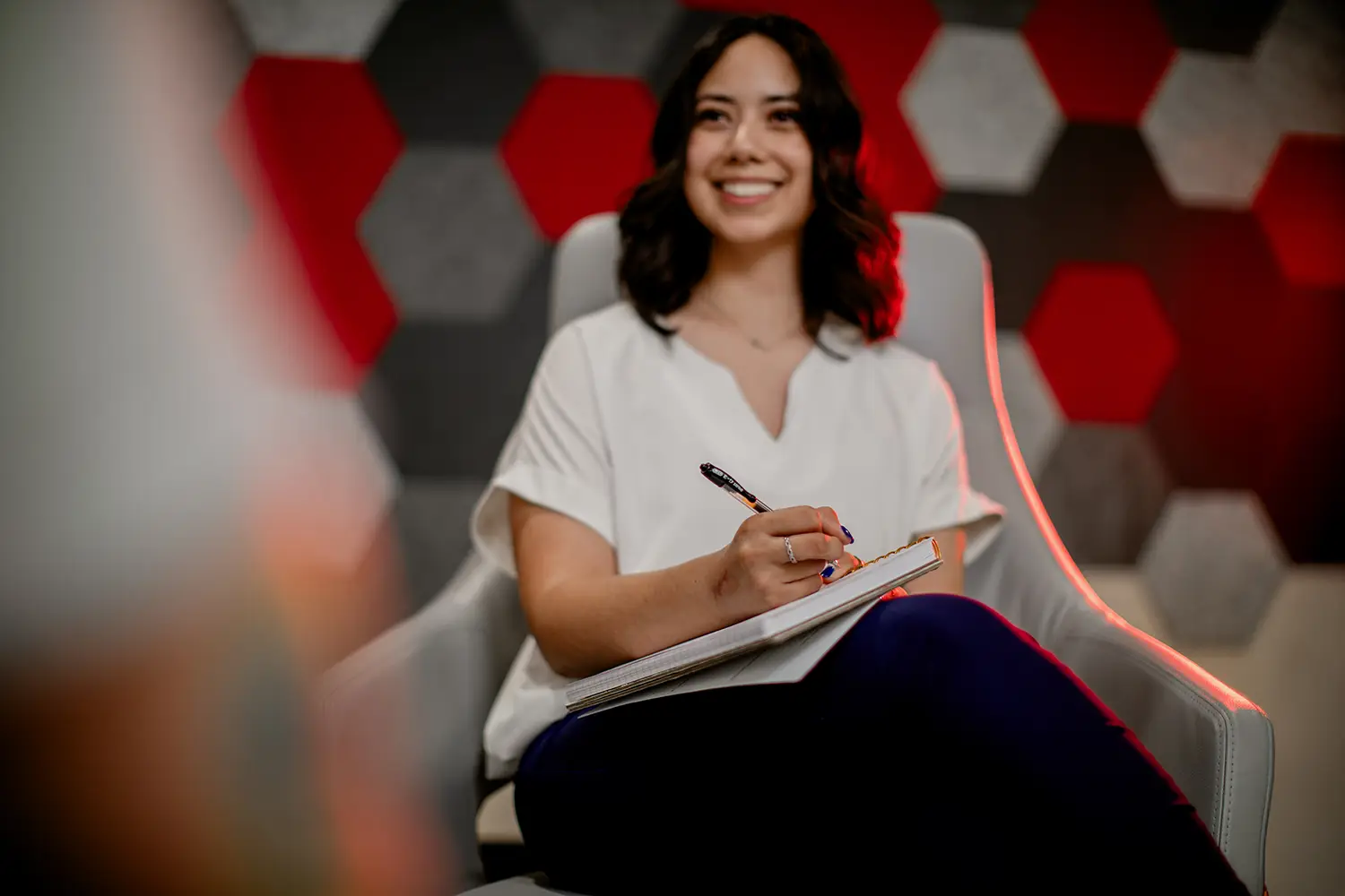 Student taking notes during a discussion in a modern campus study space with geometric wall panels