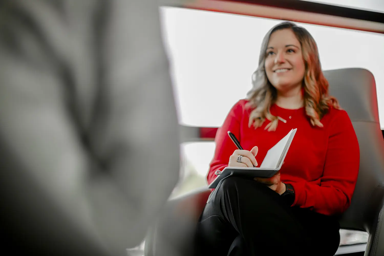 Clinical rehabilitation counseling student taking notes during a one-on-one advising or counseling session in a campus lounge area